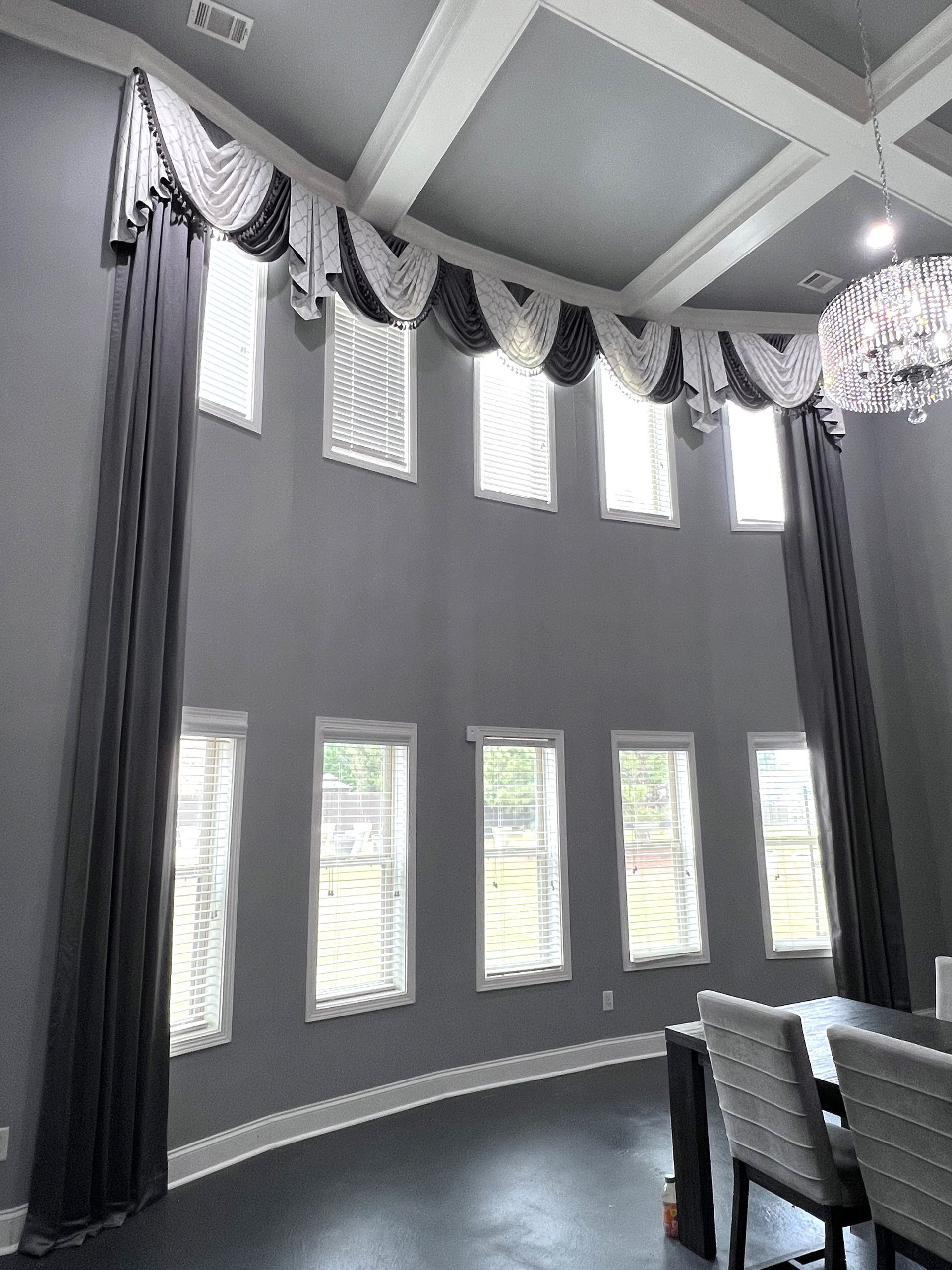 Curved dining room with tall windows, gray walls, drapes, and a chandelier ceiling fixture