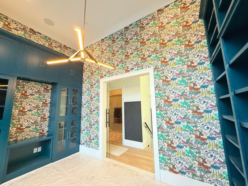 Colorful patterned wallpaper in a bright room with blue built-in cabinetry and a modern ceiling light.