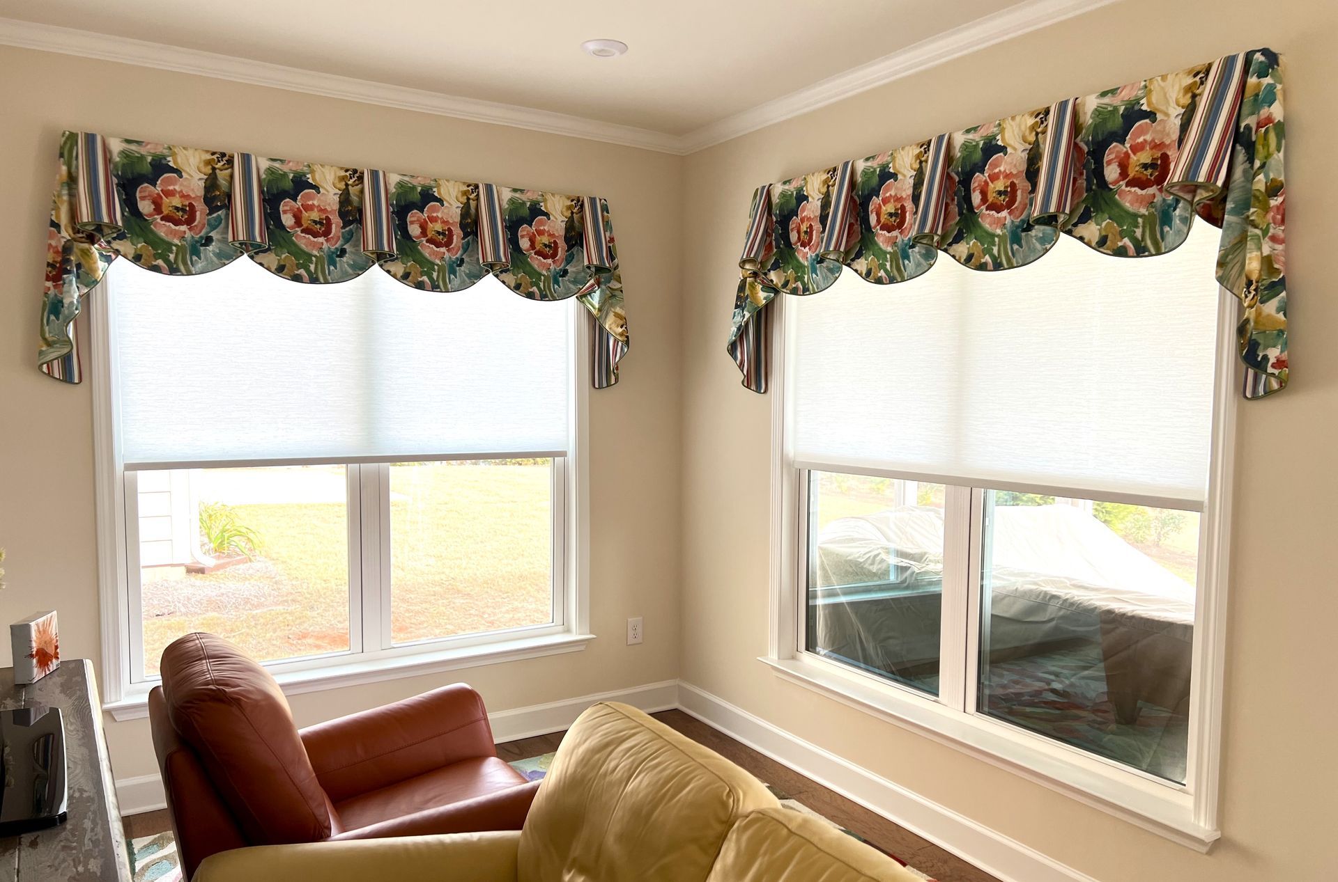 Living room corner with two windows, floral valances, and a brown armchair and sofa.