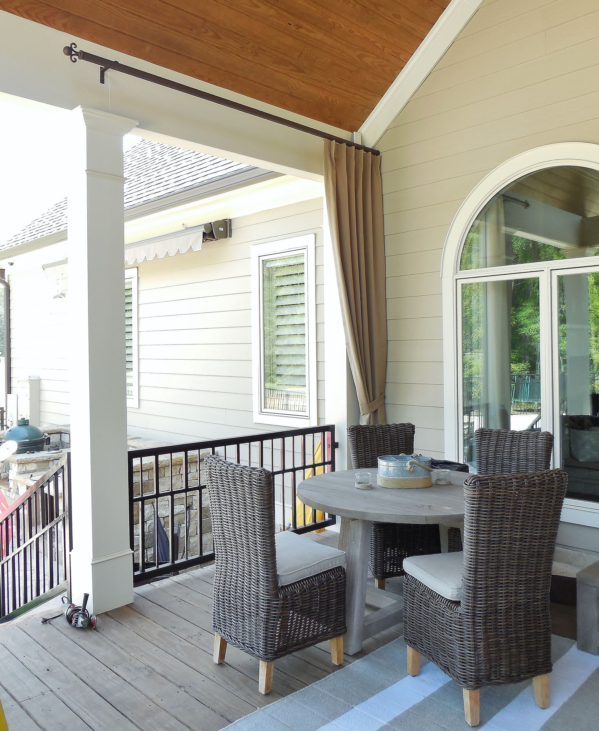 Covered patio with wicker chairs and a round table overlooking a yard