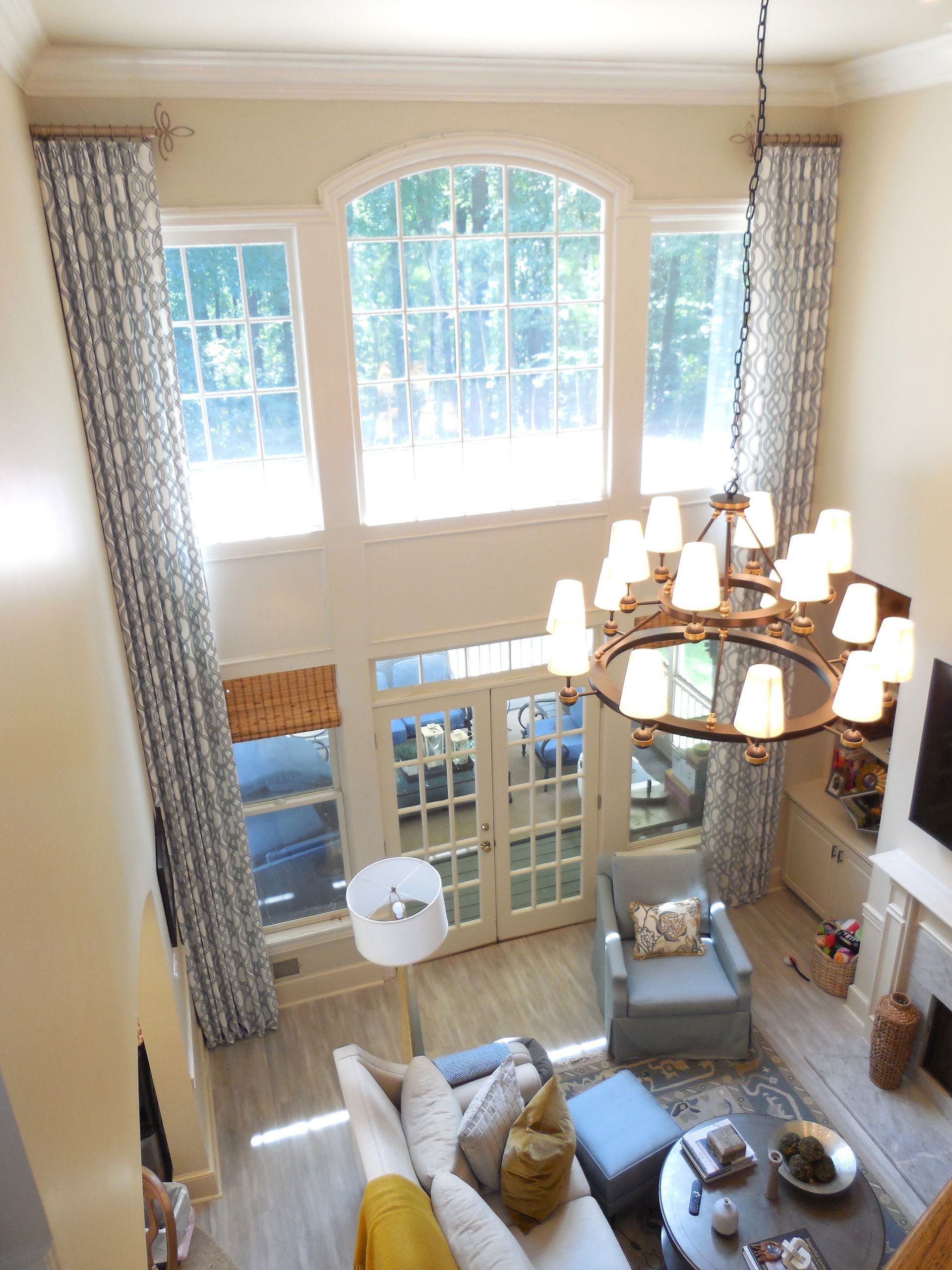 Bright, airy living room with tall windows, chandelier, and neutral sofas viewed from above