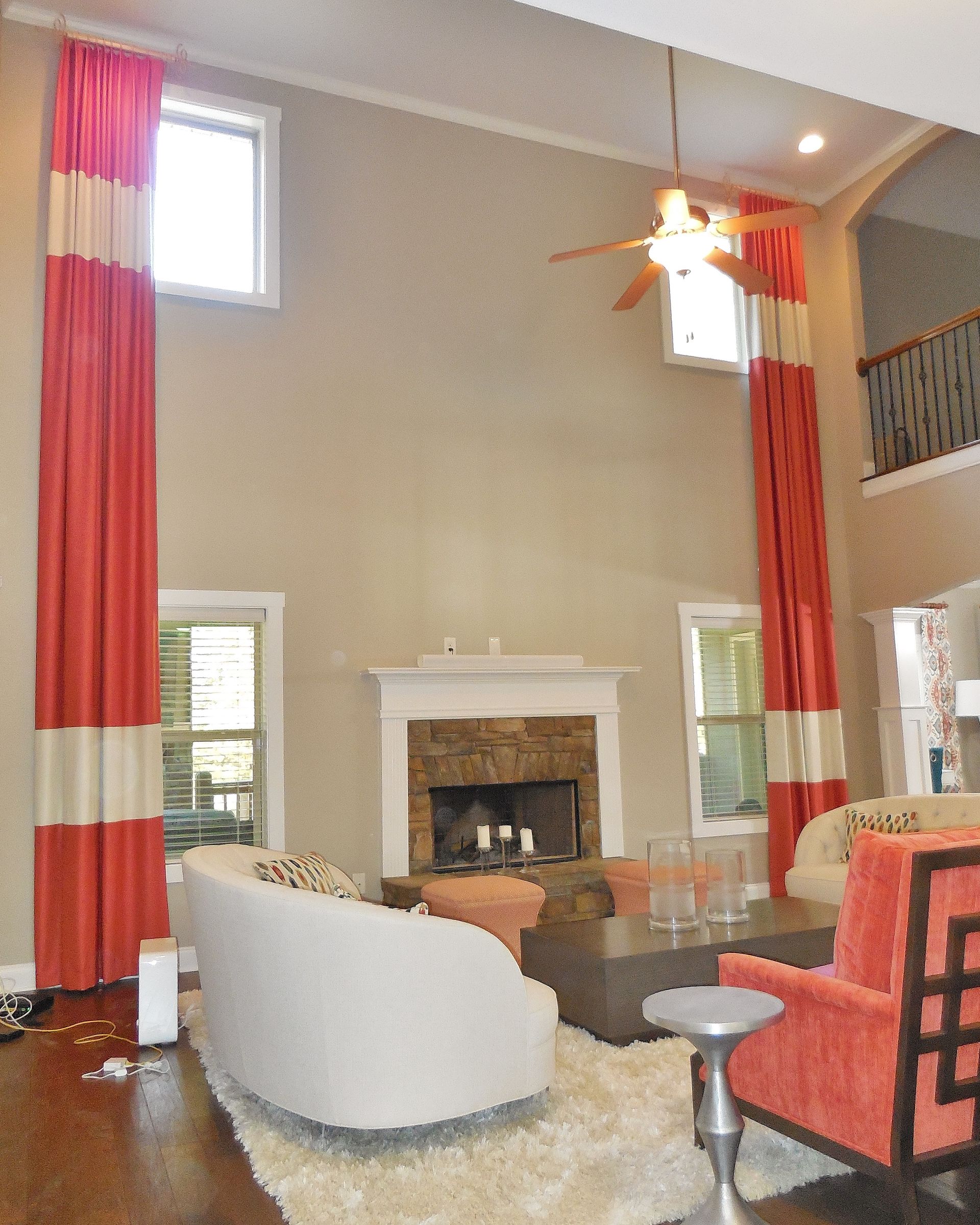 Living room with tall windows, red curtains, fireplace, and modern furniture.