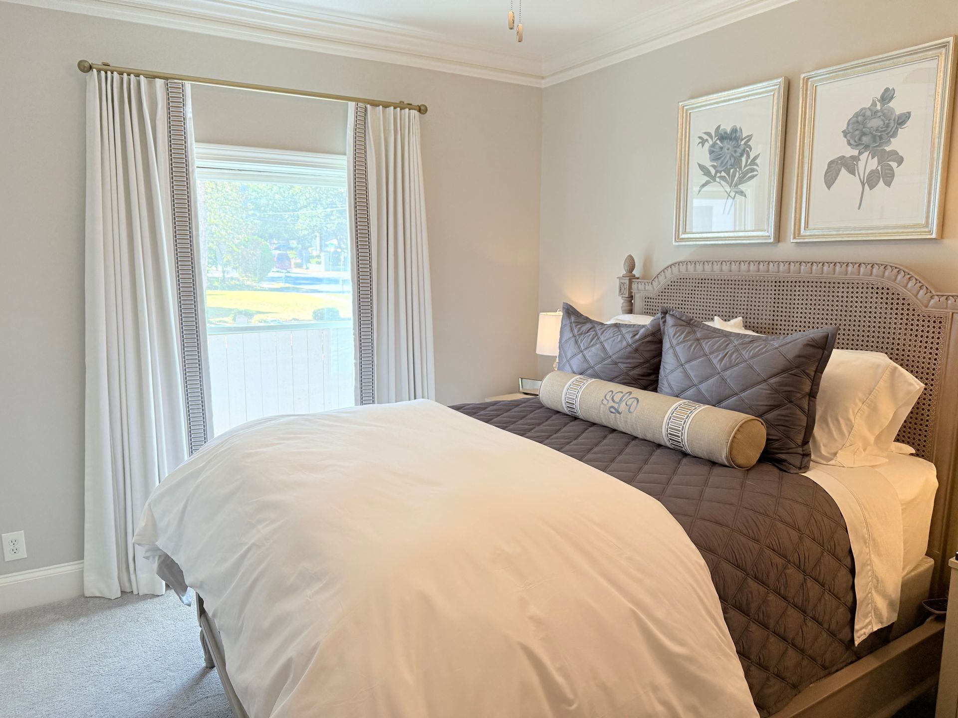 Cozy bedroom with a white bed, gray tufted headboard, and window with curtains.
