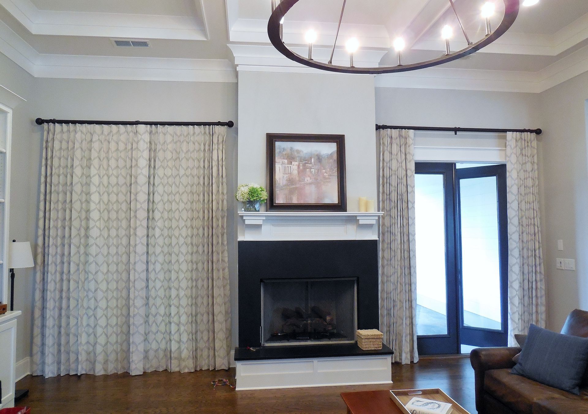 Living room with fireplace, chandelier, patterned curtains, and French doors with bright light