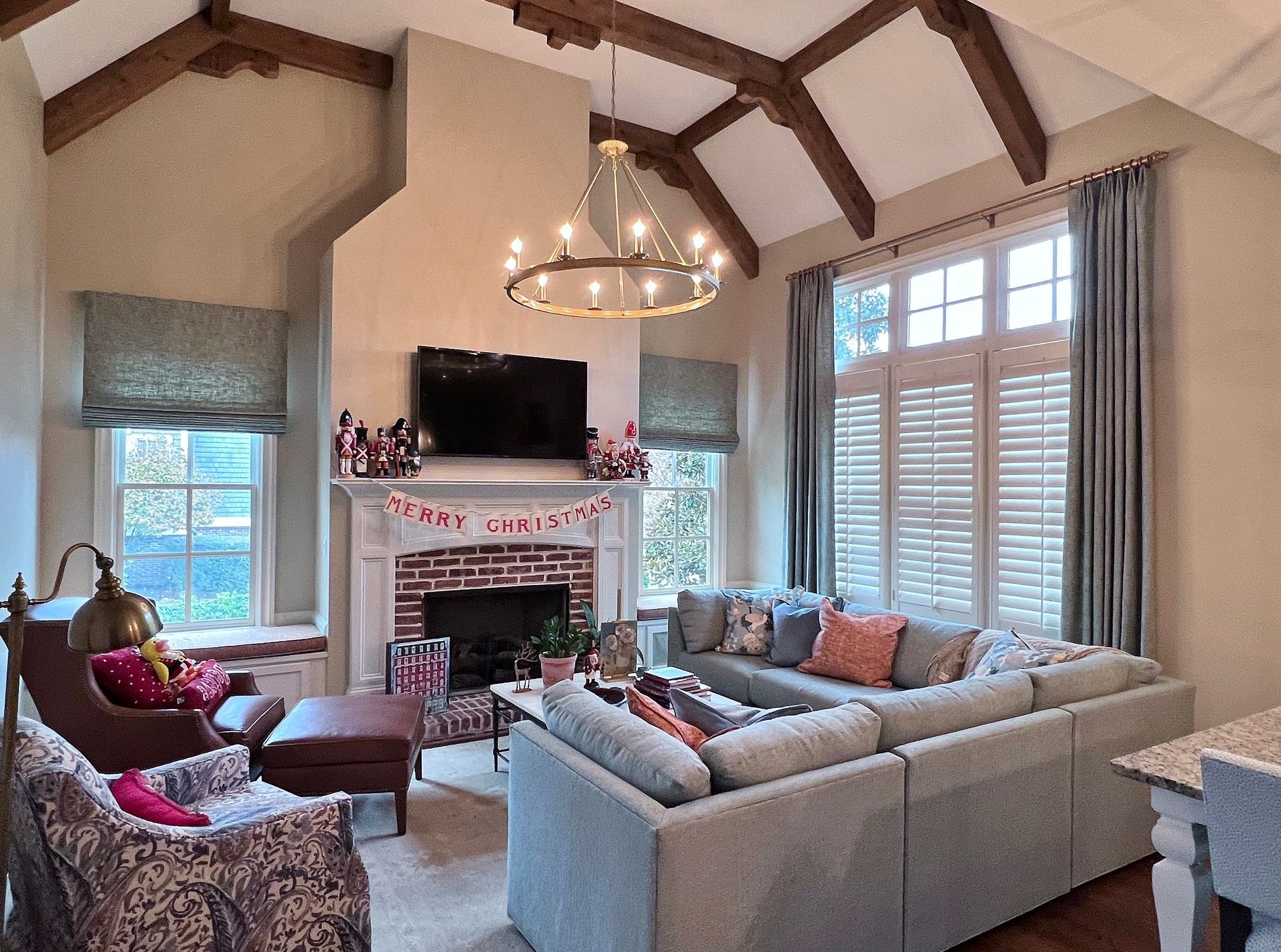 Cozy living room with sectional sofa, fireplace, chandelier, and large windows with shutters