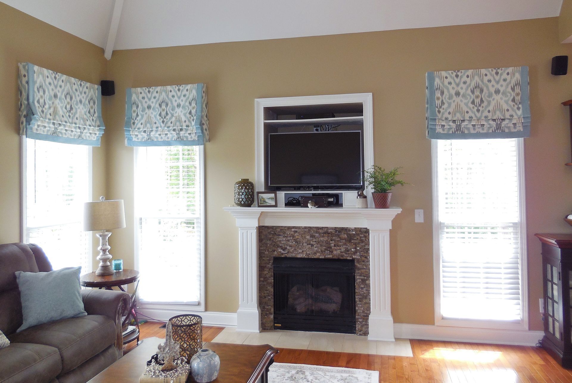 Living room with beige walls, white fireplace, windows with blue valances, and a sofa on the left
