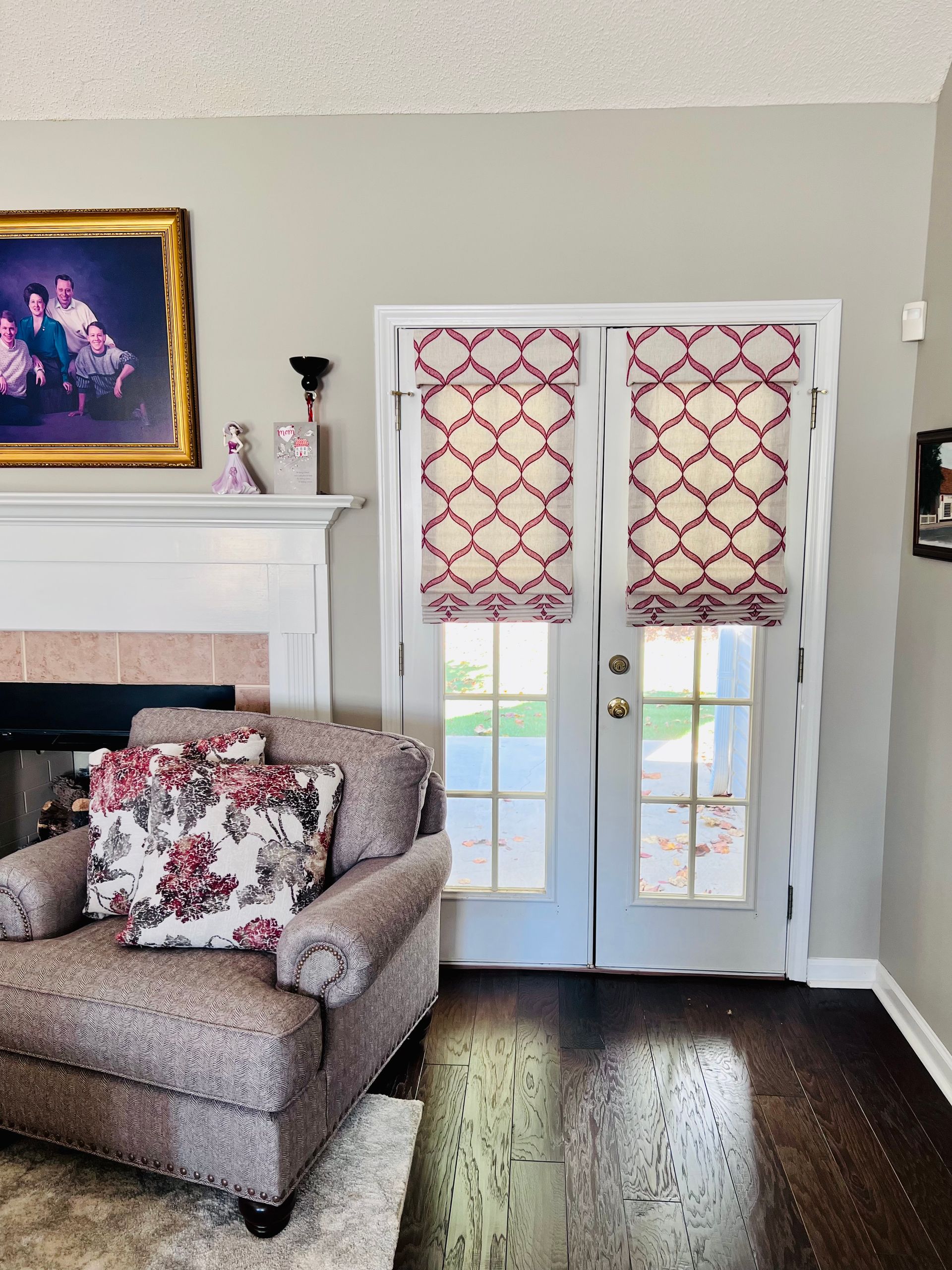 Living room with armchair, fireplace, French doors, and patterned red-and-white curtains