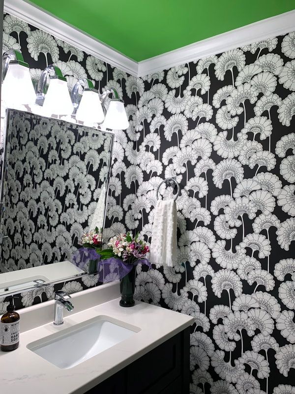 Black-and-white patterned bathroom with green ceiling, white sink, mirror, and purple flowers