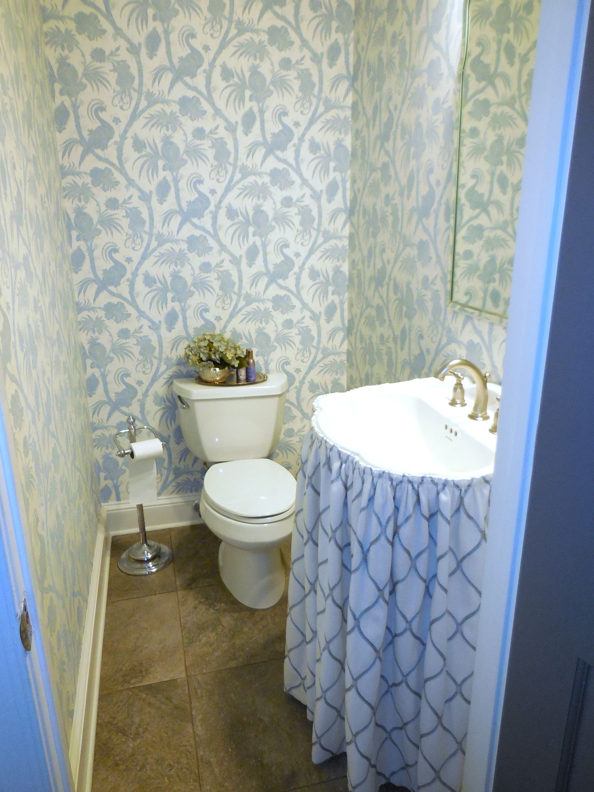 Small bathroom with white toilet, pedestal sink, beige carpet, and blue patterned wallpaper.