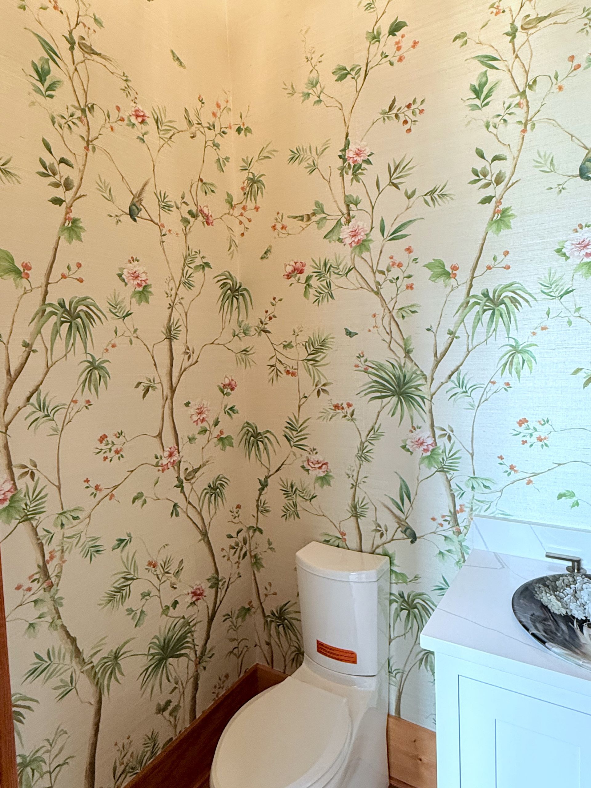 Small bathroom with floral wallpaper, white toilet, and a sink or cabinet at the right edge.