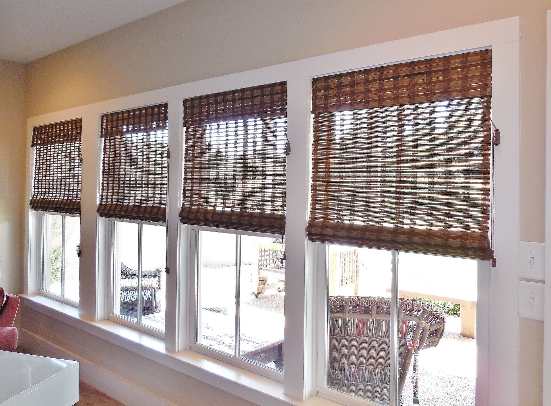 Window row with brown woven blinds over a bright outdoor view in a room