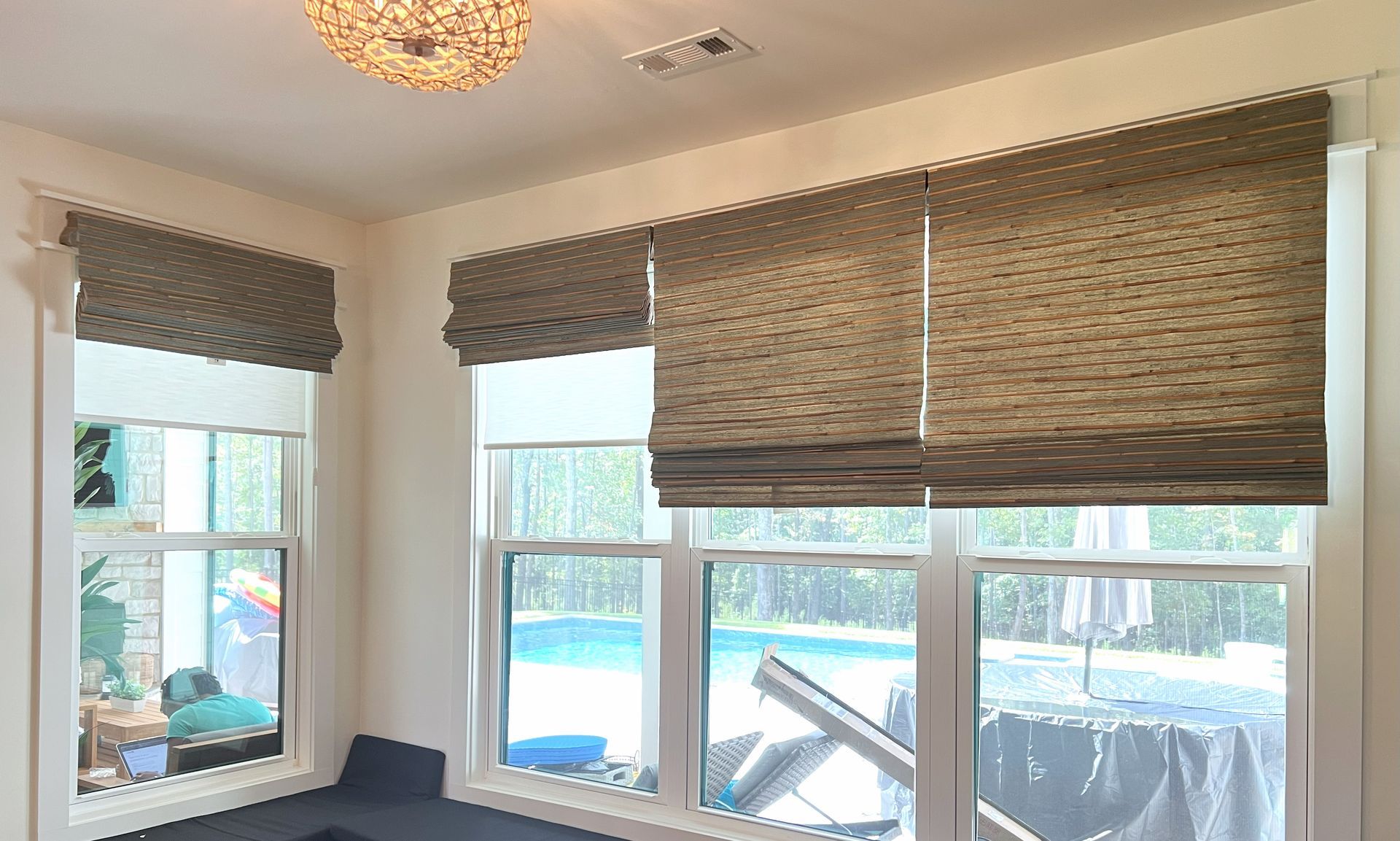 Bright room with blue walls, woven blinds, and two large windows overlooking a patio.