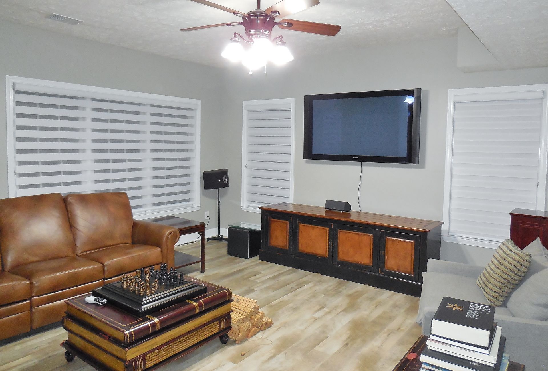Modern living room with leather sofa, wall-mounted TV, and white shutters