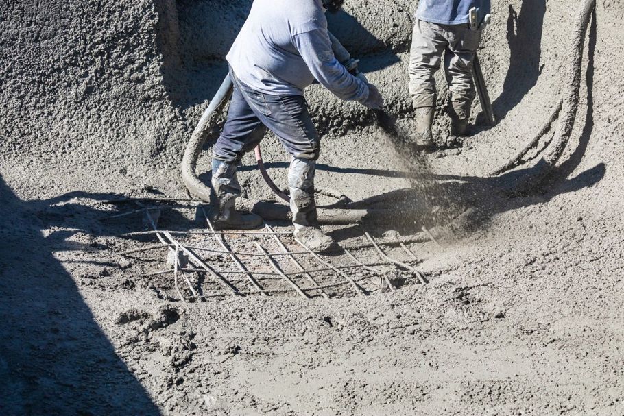 Workers pouring concrete over rebar for a stable patio foundation.