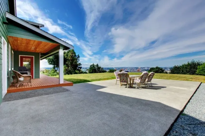 Spacious backyard concrete patio with a scenic view and seating.