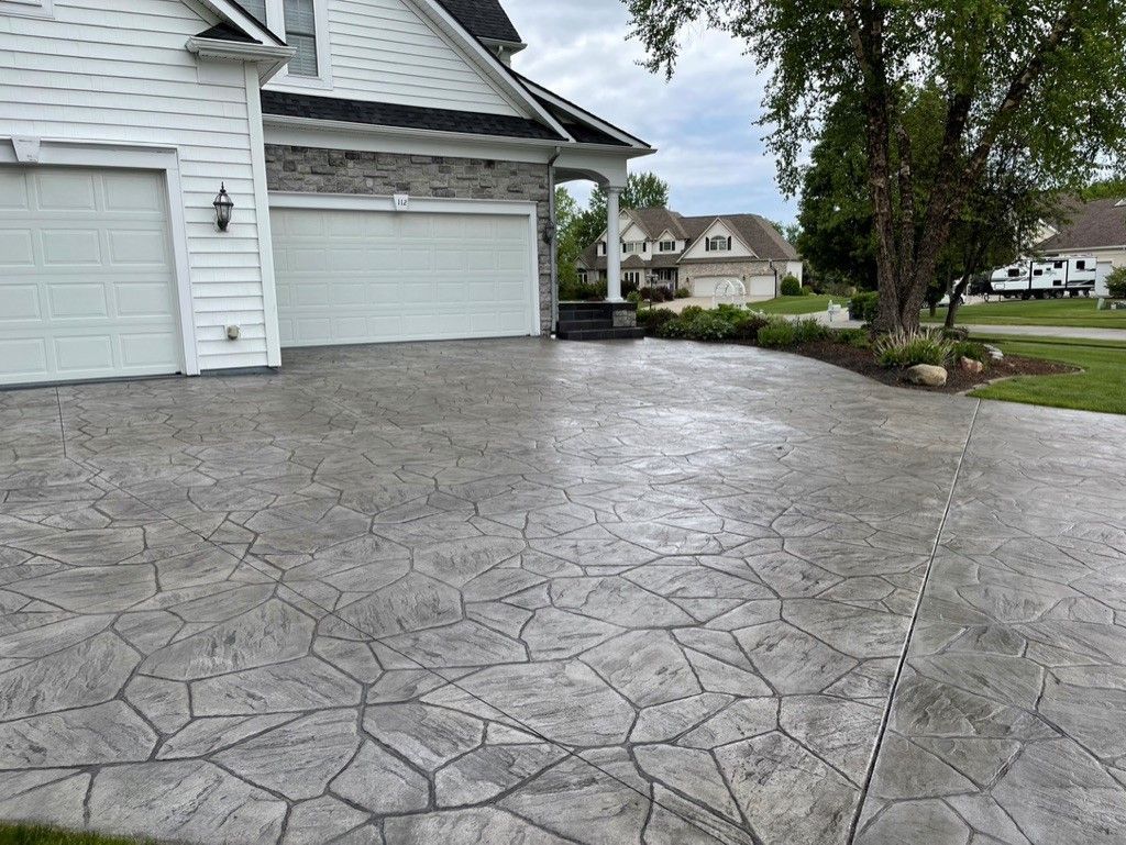 Textured ashlar slate stamped concrete driveway for a suburban home.