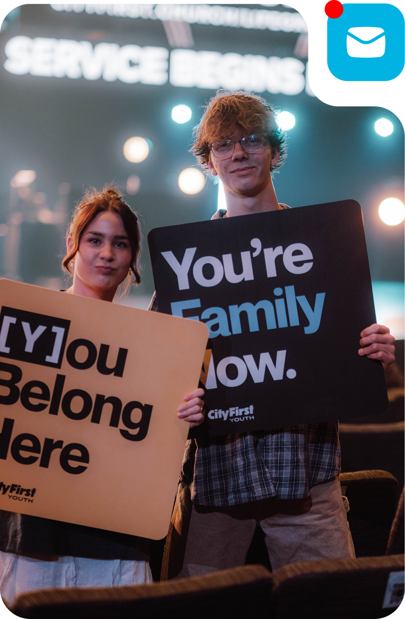 Two people holding signs at a service event, one saying