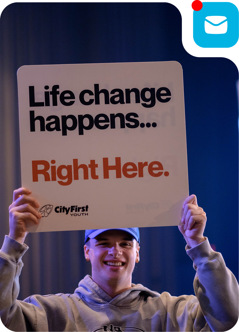 Person holding a sign that reads “Life change happens… Right Here.”
