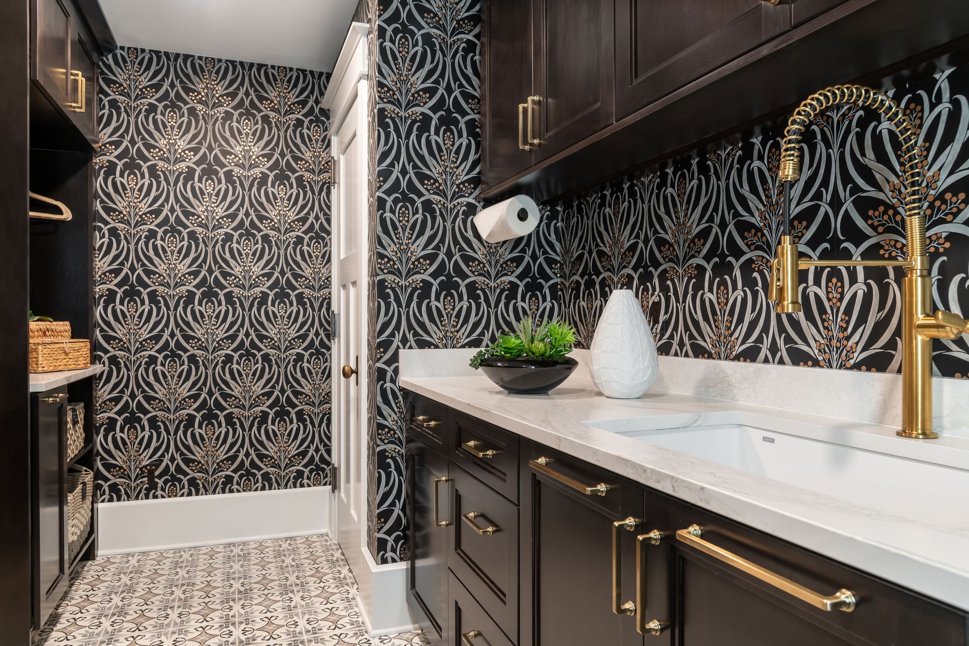 A laundry room with black and gold cabinets and a sink.