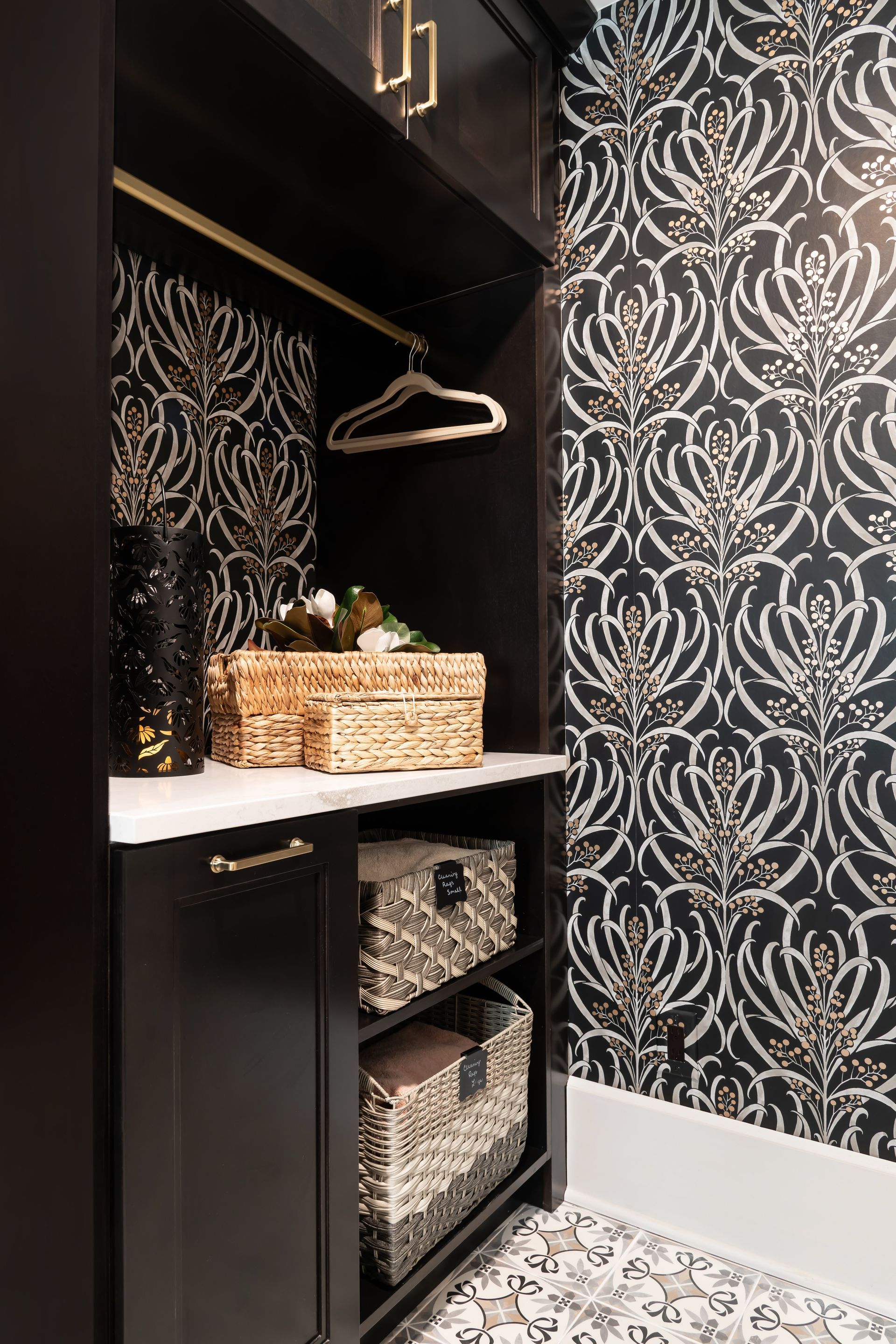 A laundry room with black and silver wallpaper and baskets on shelves.