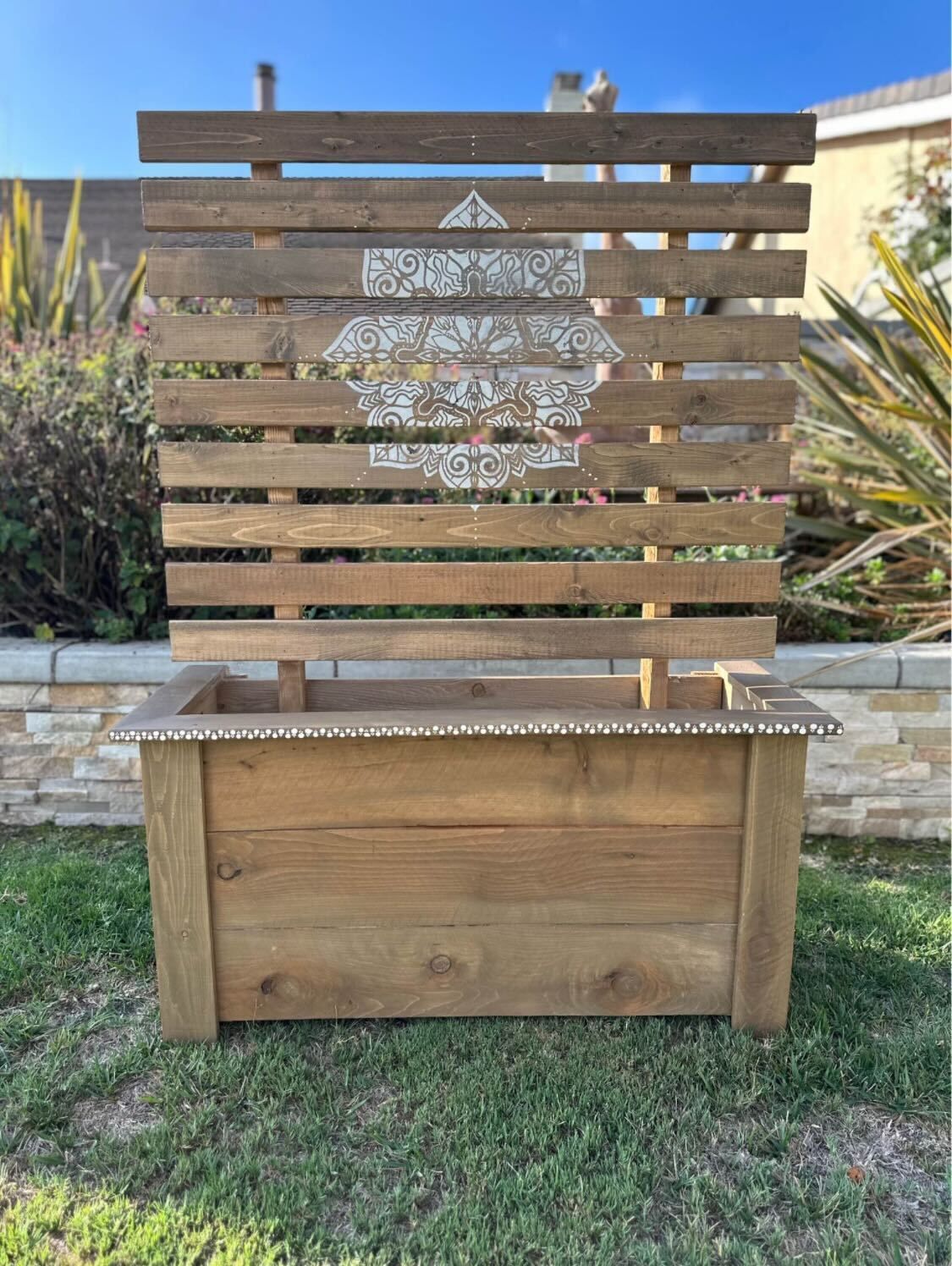 Wooden outdoor bench with slatted backrest and a decorative metal heart panel on grass.