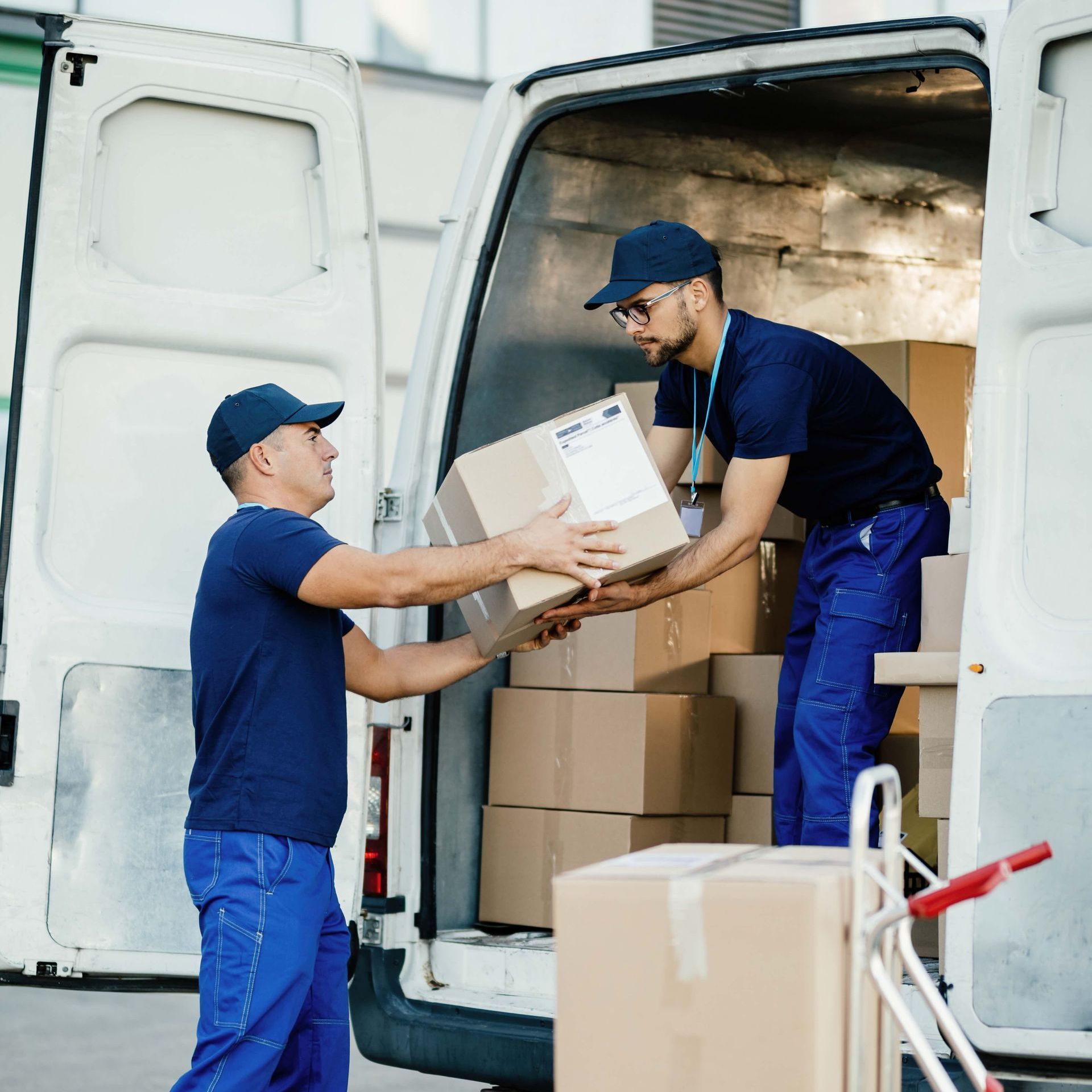 two delivery men are loading boxes into a white van