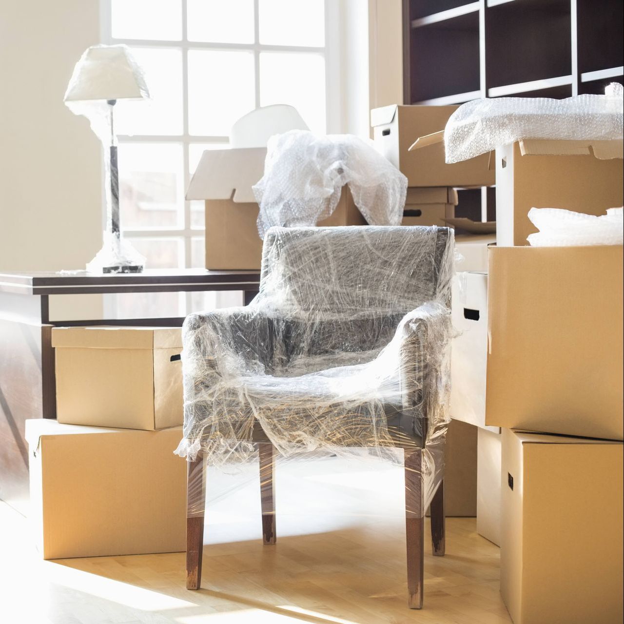 A chair is wrapped in plastic and surrounded by cardboard boxes.