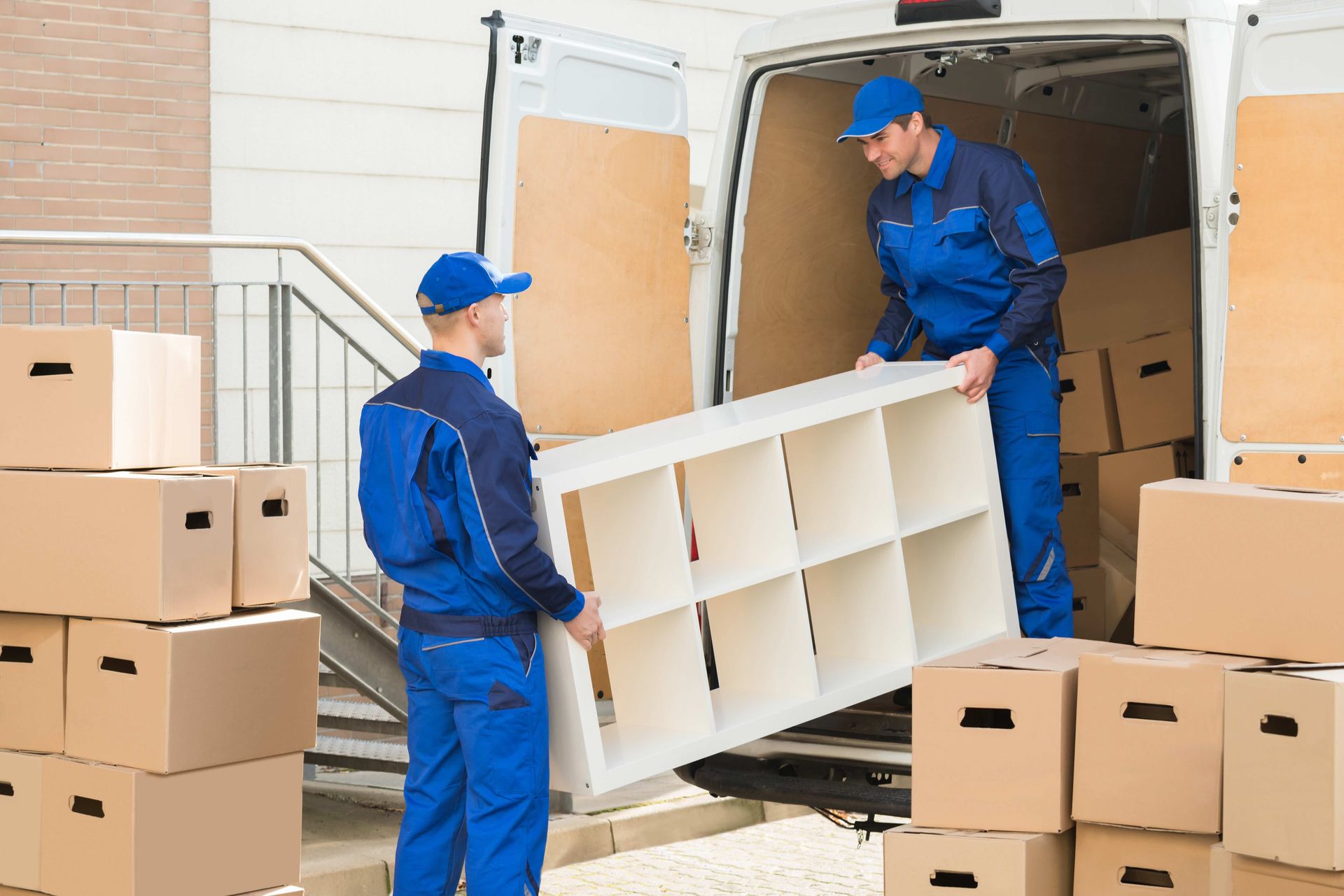 two men are carrying a shelf out of a van