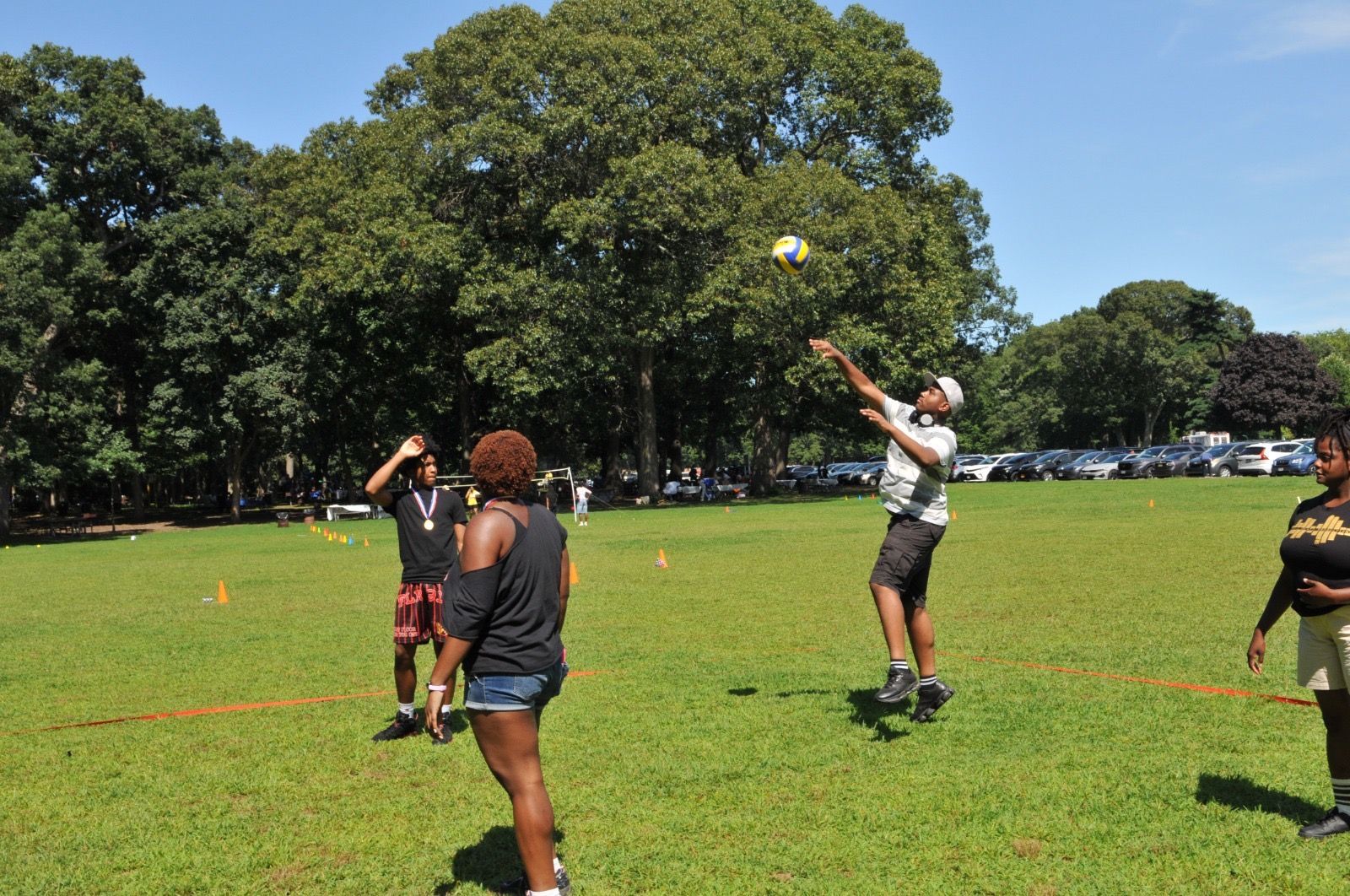 People playing catch on a sunny grassy field with trees in the background