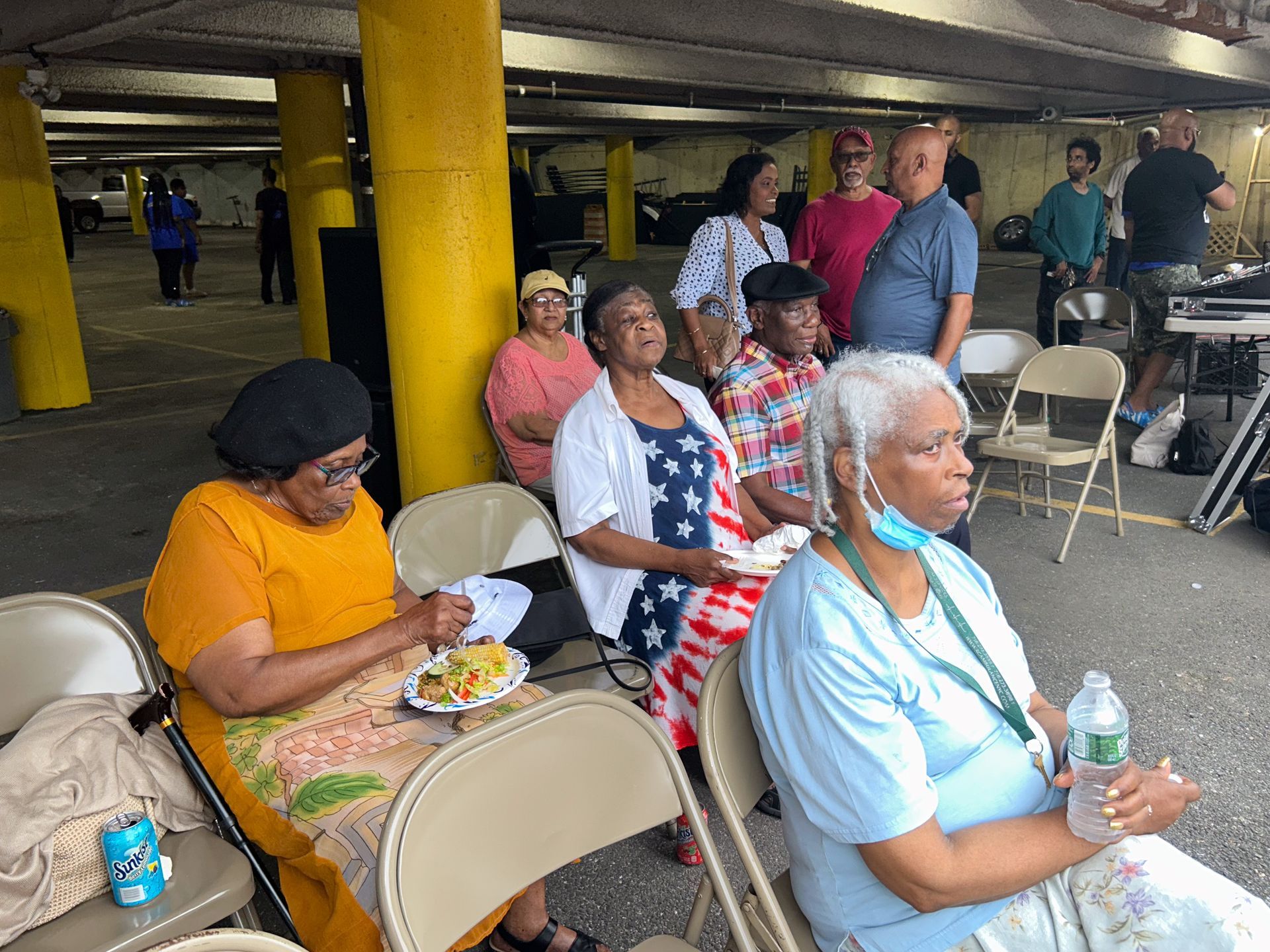 A group of people are sitting in chairs in a parking garage.