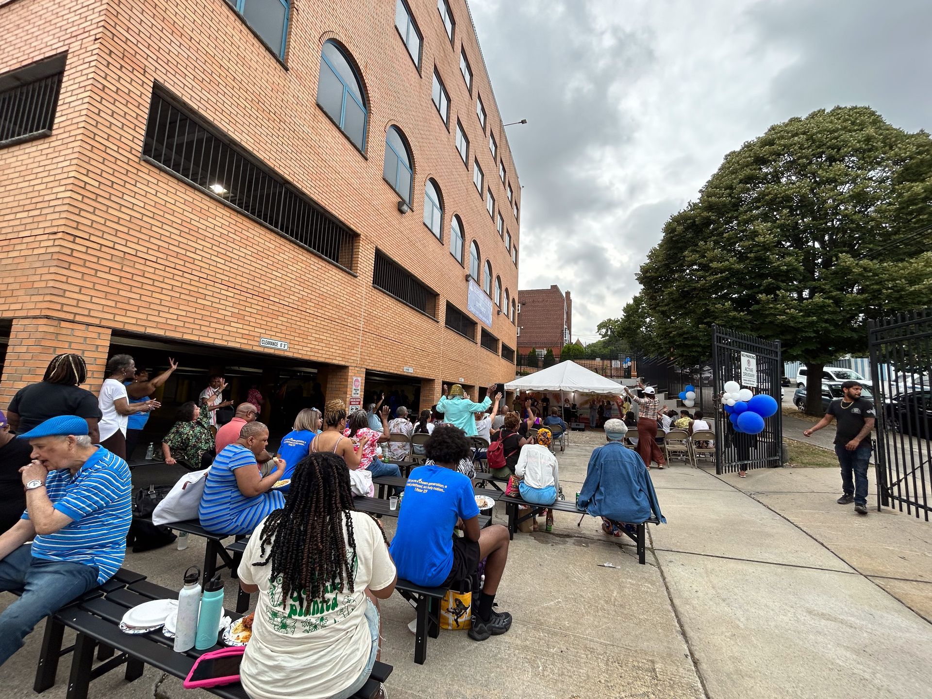 A group of people are sitting on benches outside of a building.