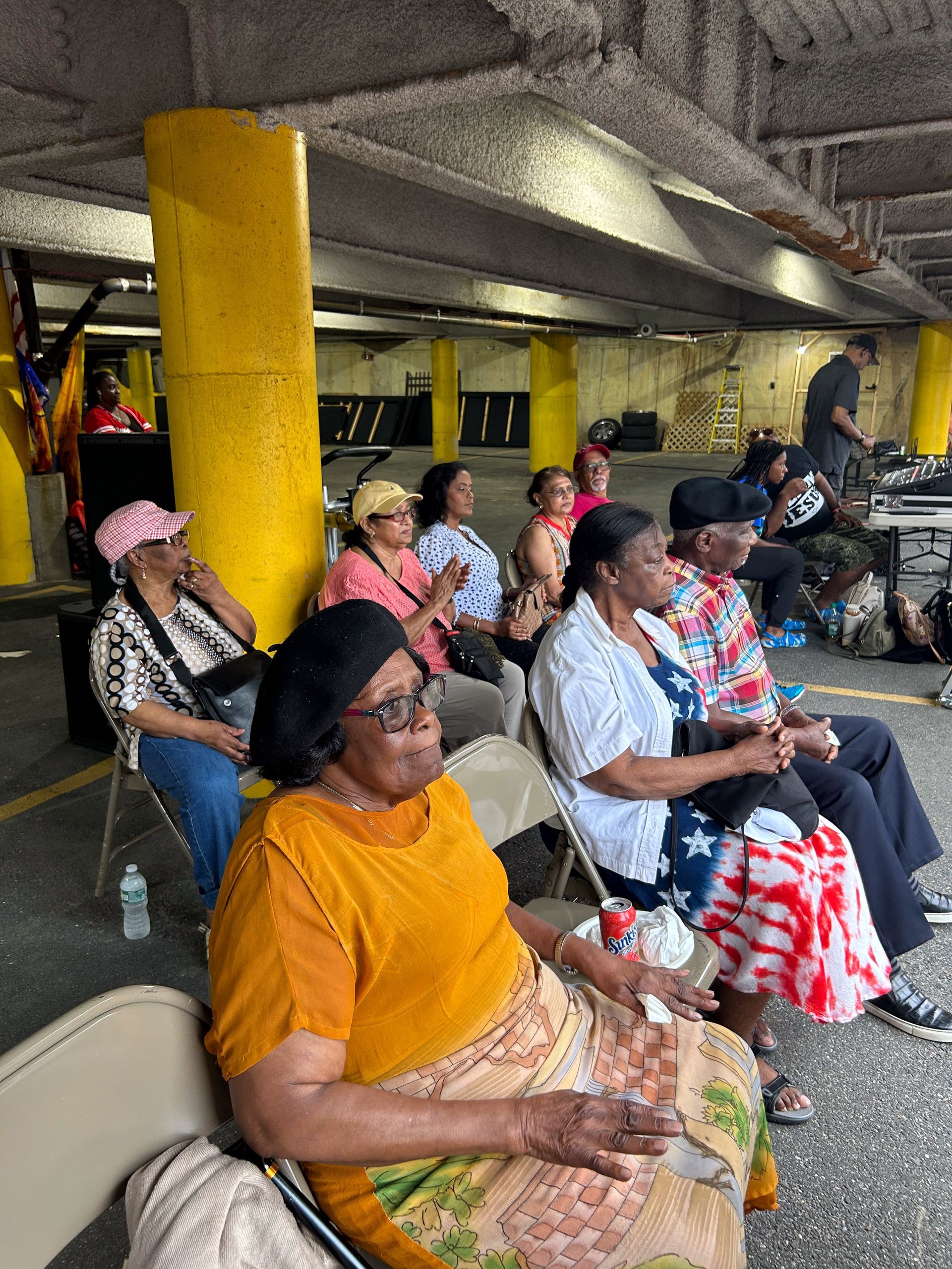 A group of people are sitting in chairs in a parking garage.