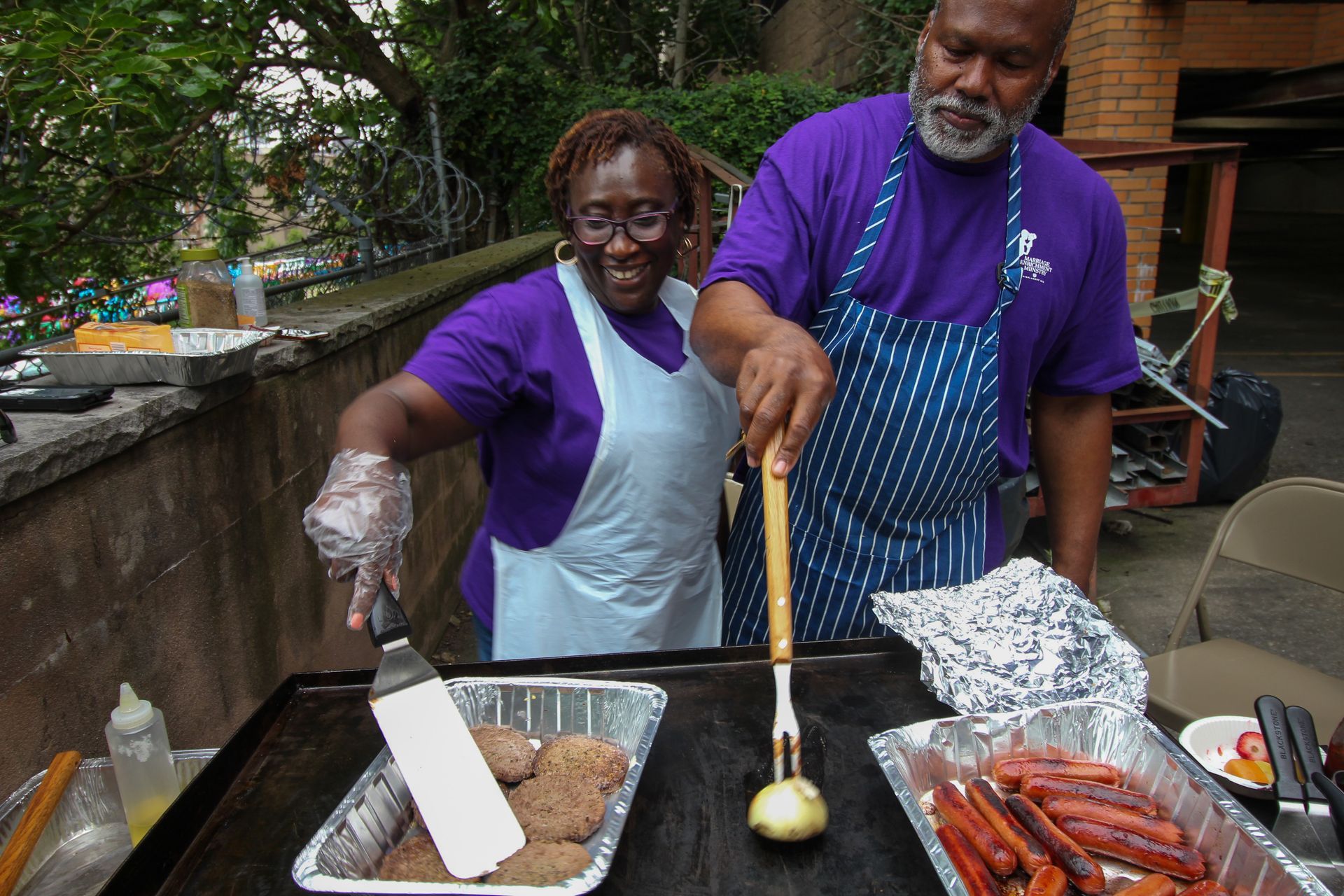 A man and a woman are preparing food on a grill