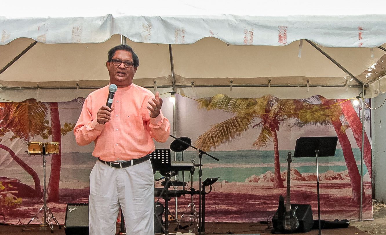 A man is standing in front of a tent holding a microphone.
