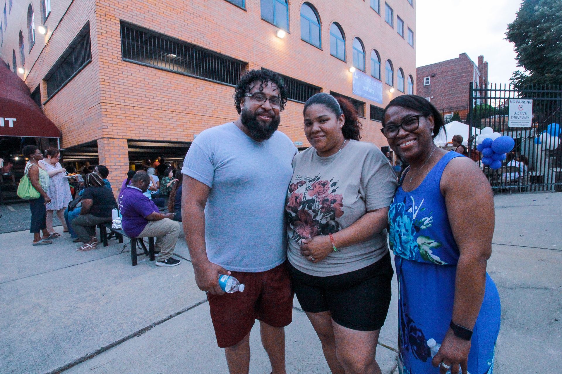 A man and two women are posing for a picture in front of a building.