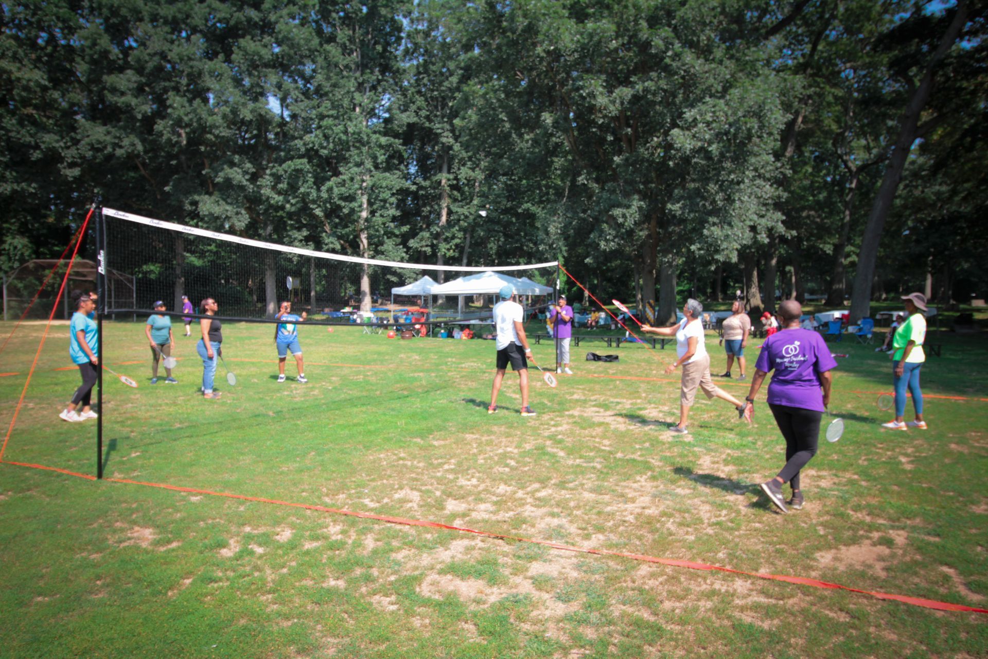 A group of people are playing volleyball in a park.