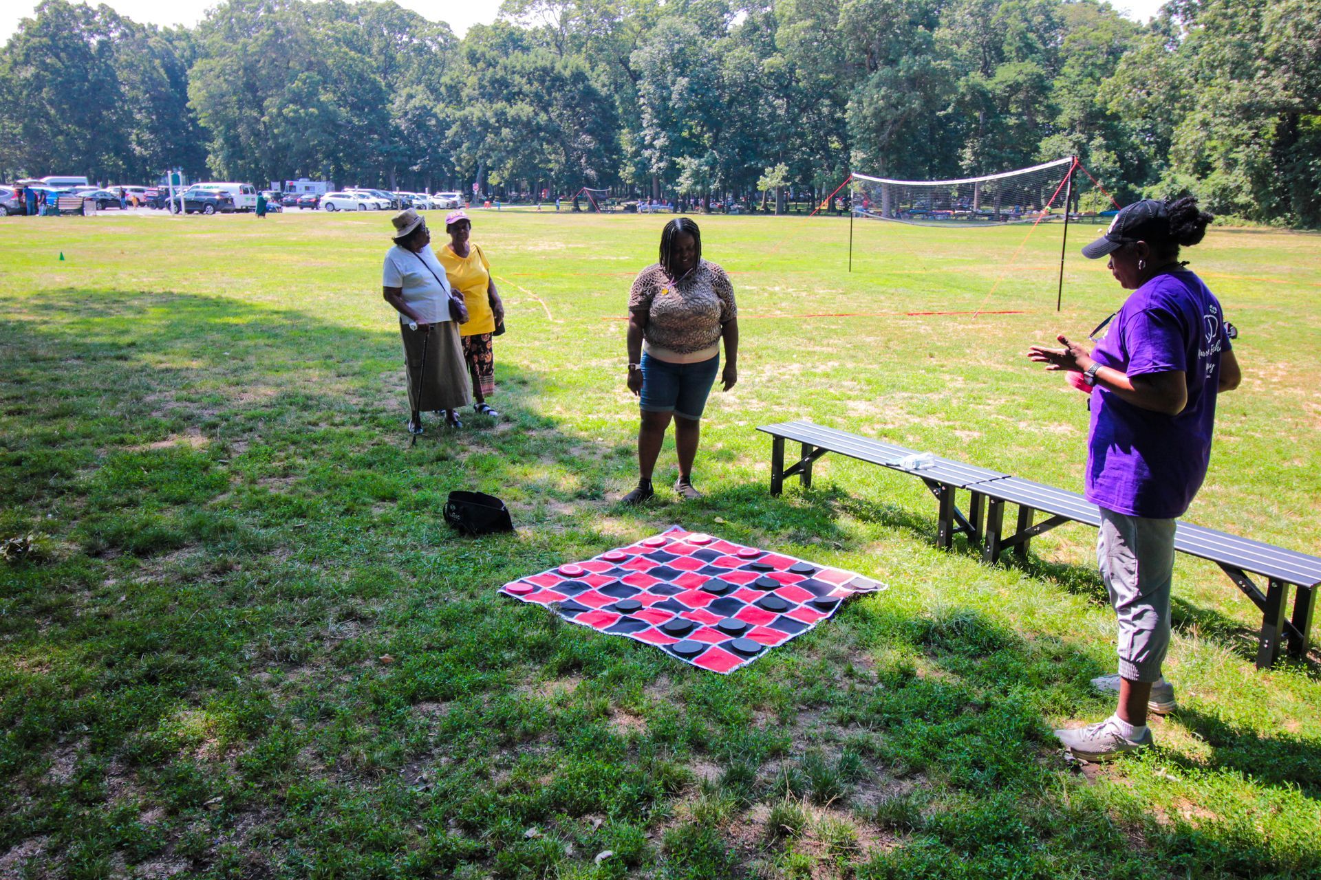 A group of people are standing in a field with a blanket in the middle.
