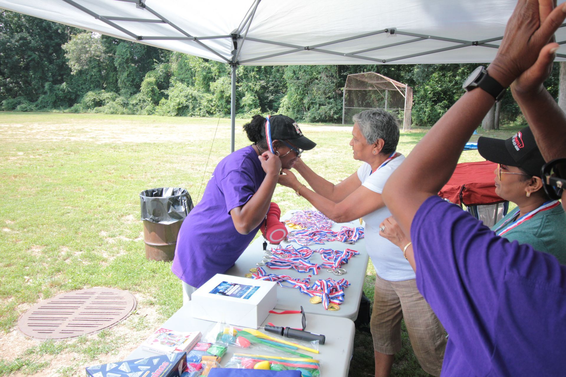 A group of people are standing around a table under a tent.
