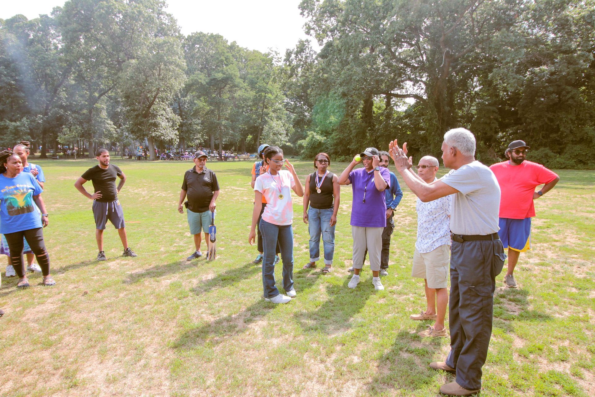 A group of people are standing in a circle in a grassy field.