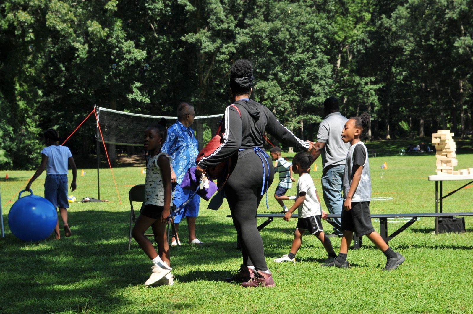 People playing soccer in a park with a ball, grassy field, and trees in the background