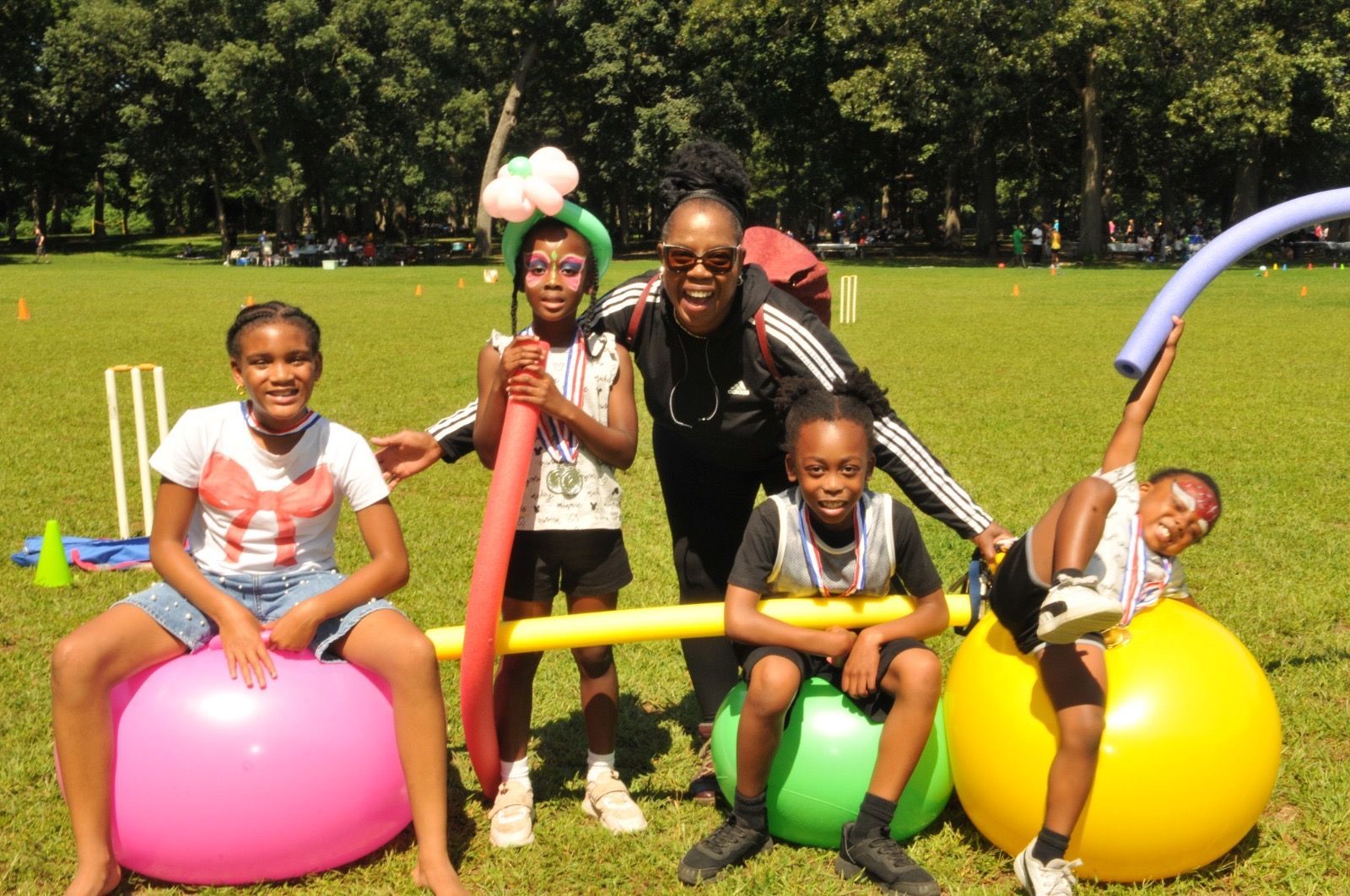 Children posing and playing on colorful bouncing balls in a sunny park