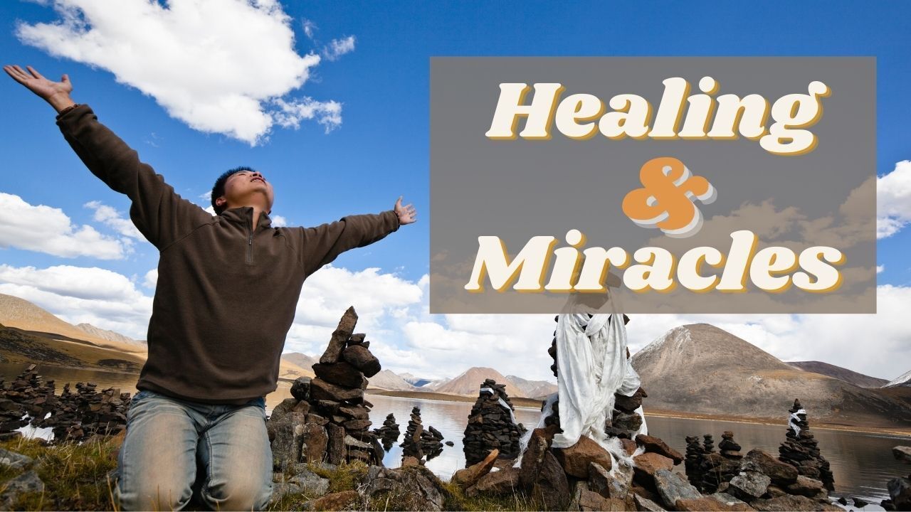 A man is kneeling down with his arms outstretched in front of a sign that says healing and miracles