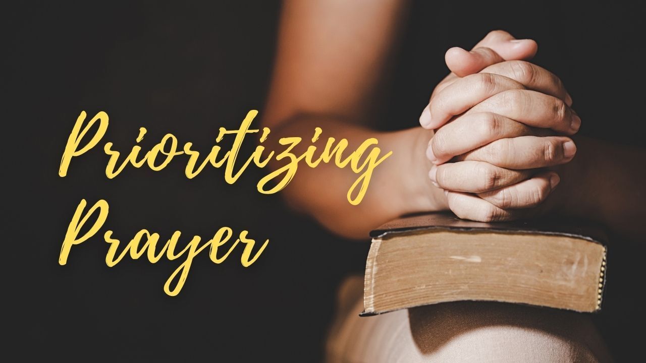 A person is praying with their hands folded over a bible.