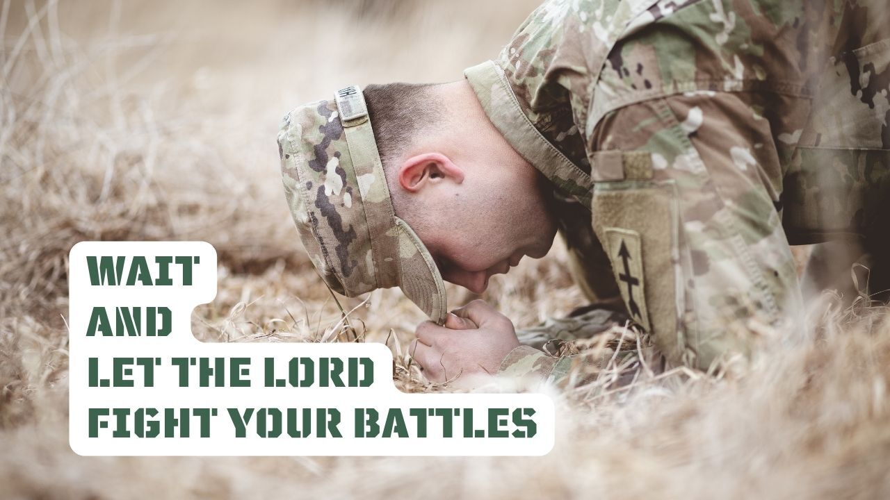 A soldier is kneeling down in the grass with his head down.