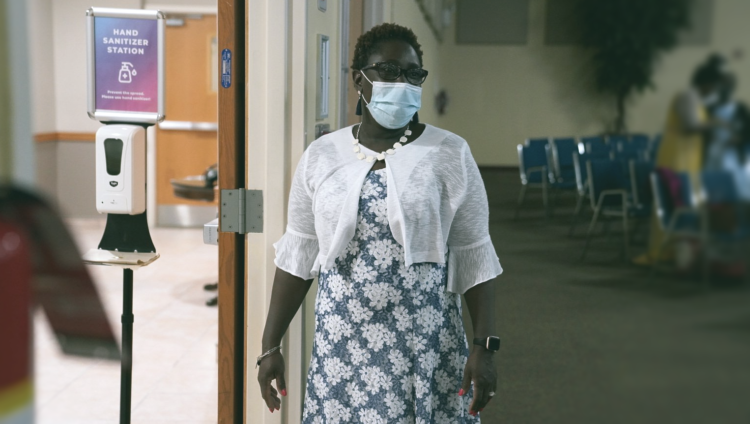 A woman wearing a mask is walking through a doorway.