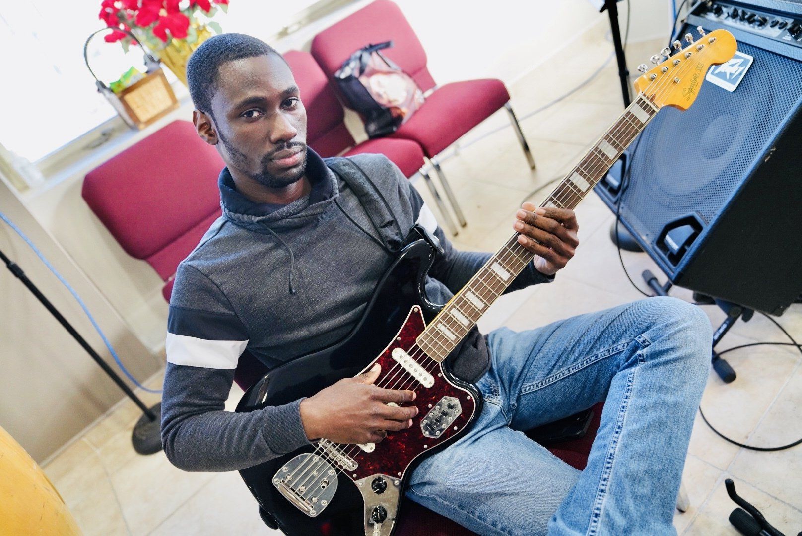 A man is sitting on the floor playing a guitar