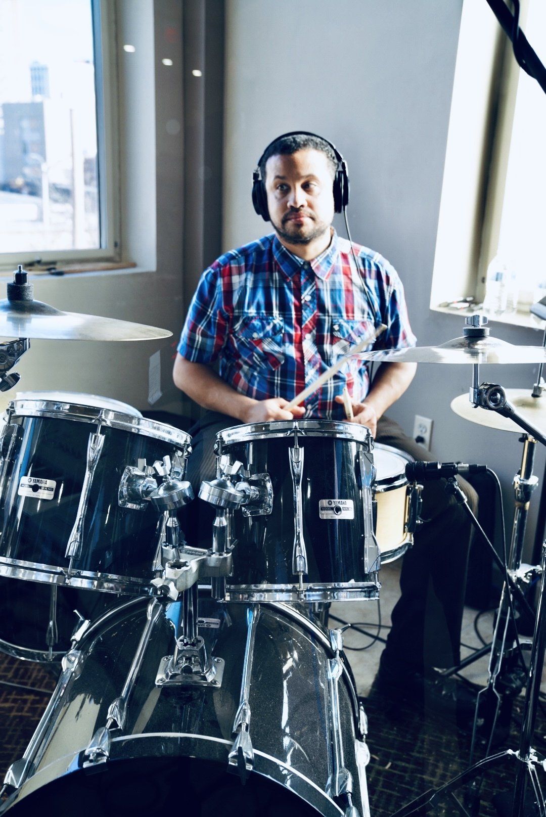 A man wearing headphones is playing drums in a room.