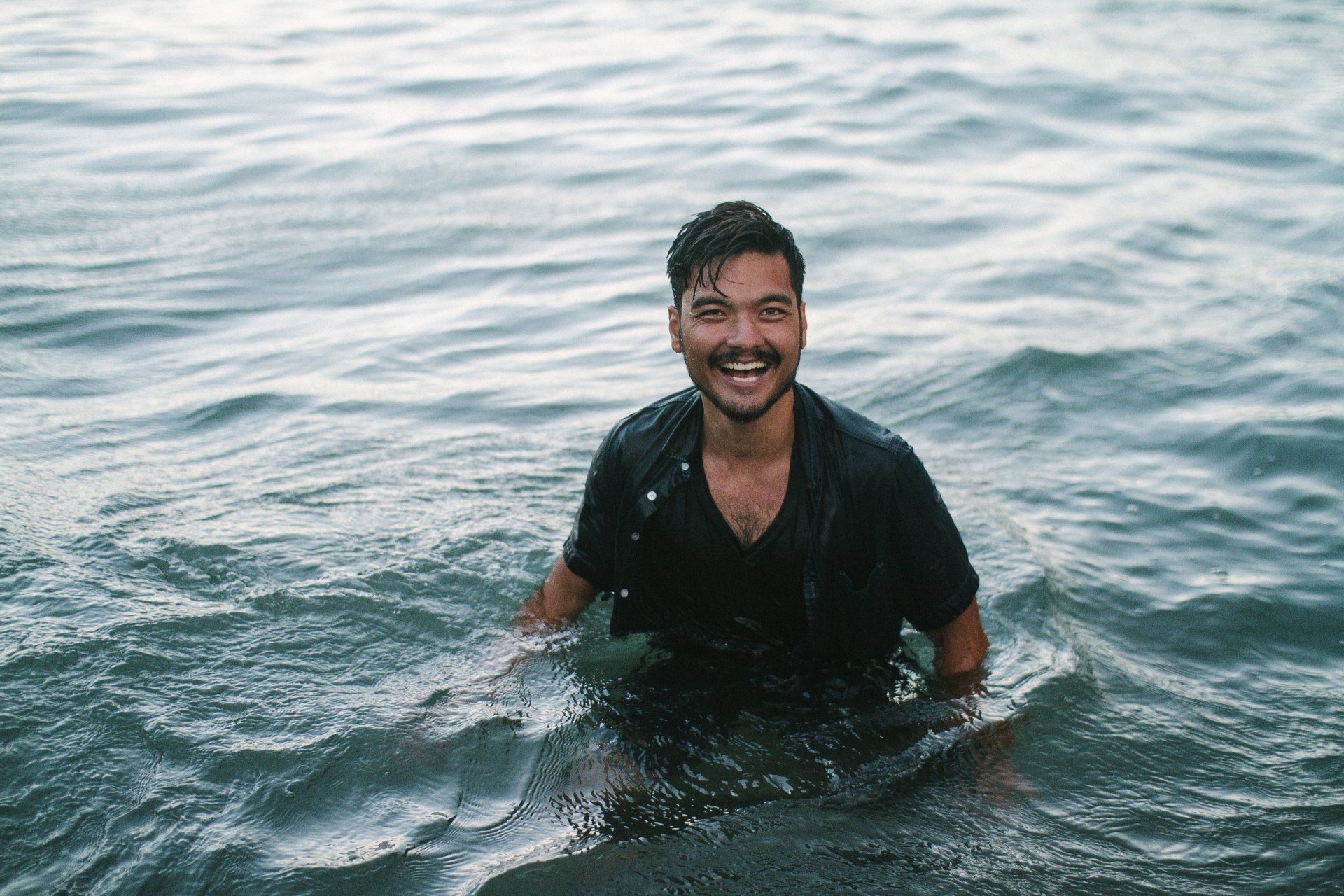 A man is swimming in the ocean and smiling.