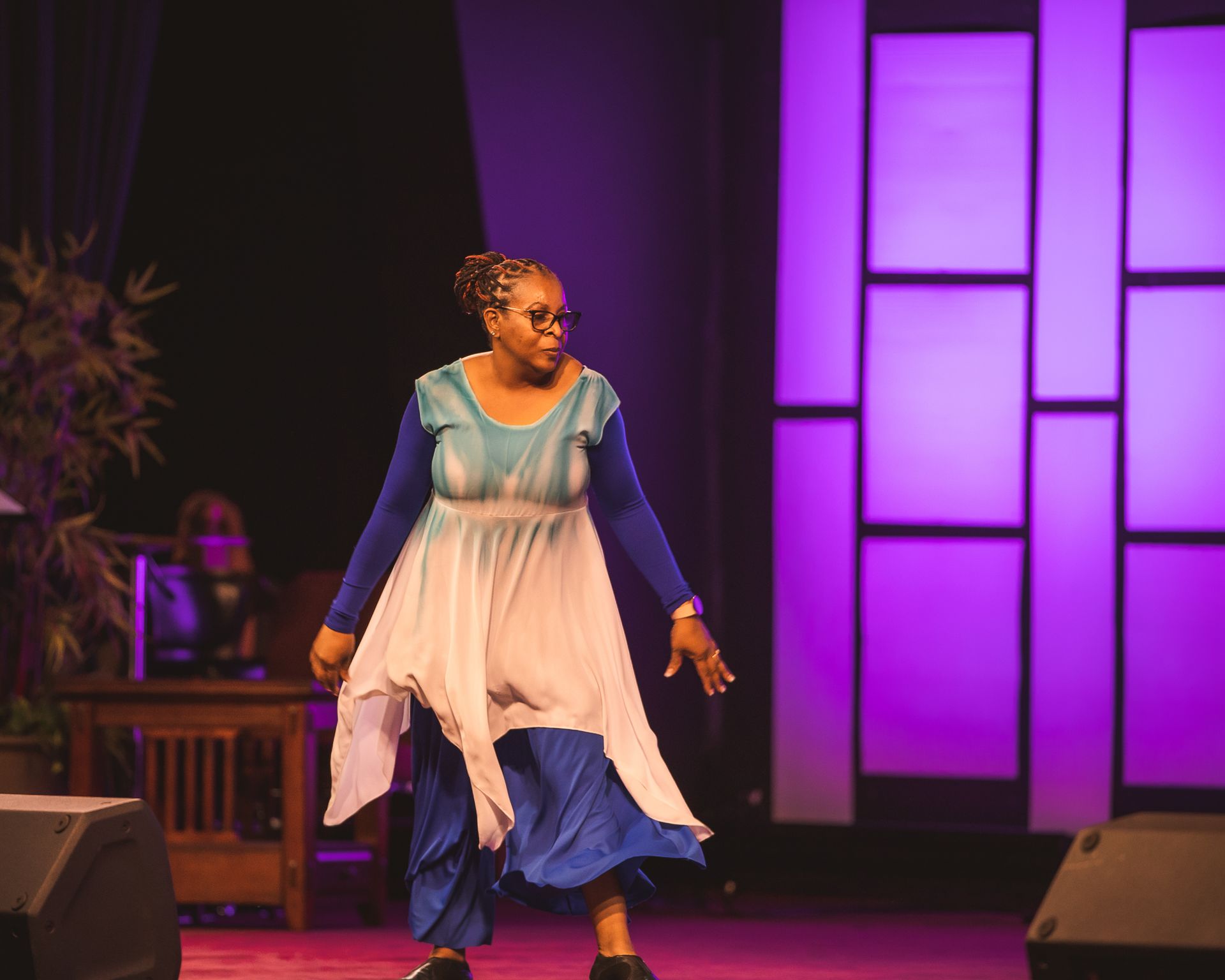 A woman in a blue and white dress is dancing on a stage.