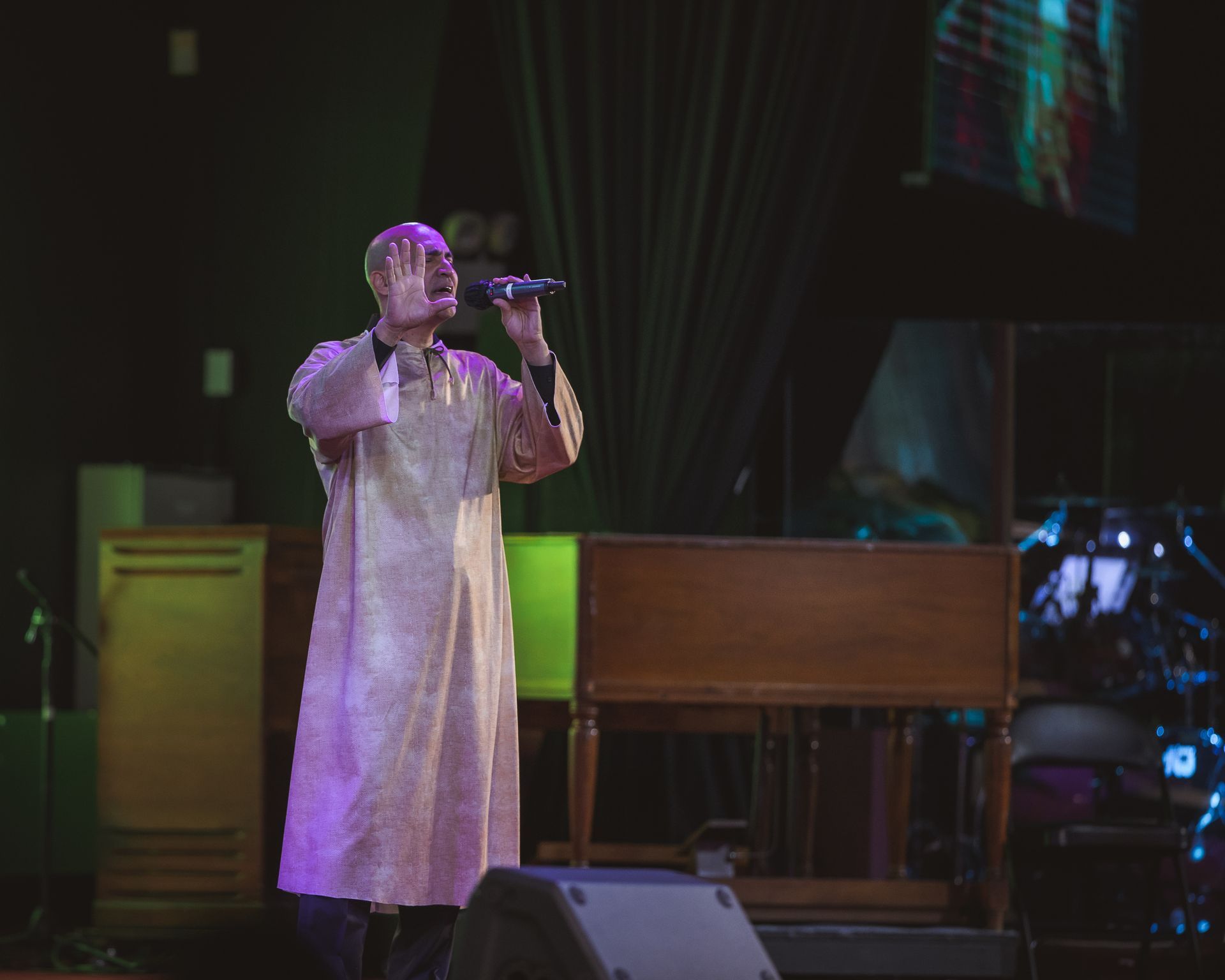 A man is singing into a microphone on a stage.